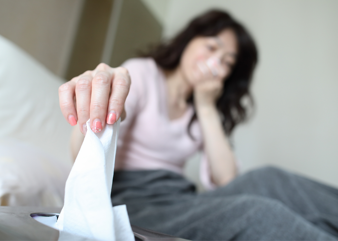 Woman sick with fever reaching for tissue.