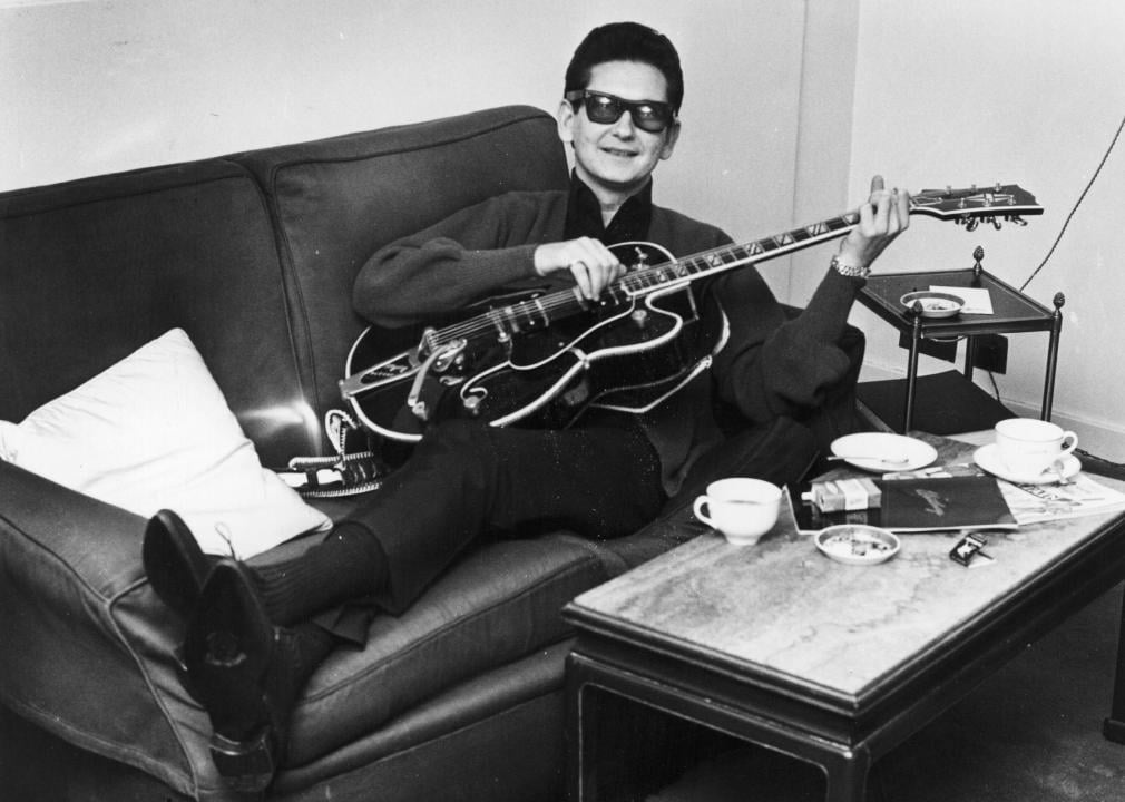 Roy Orbison strumming a guitar on the sofa of his room in the Westbury Hotel.