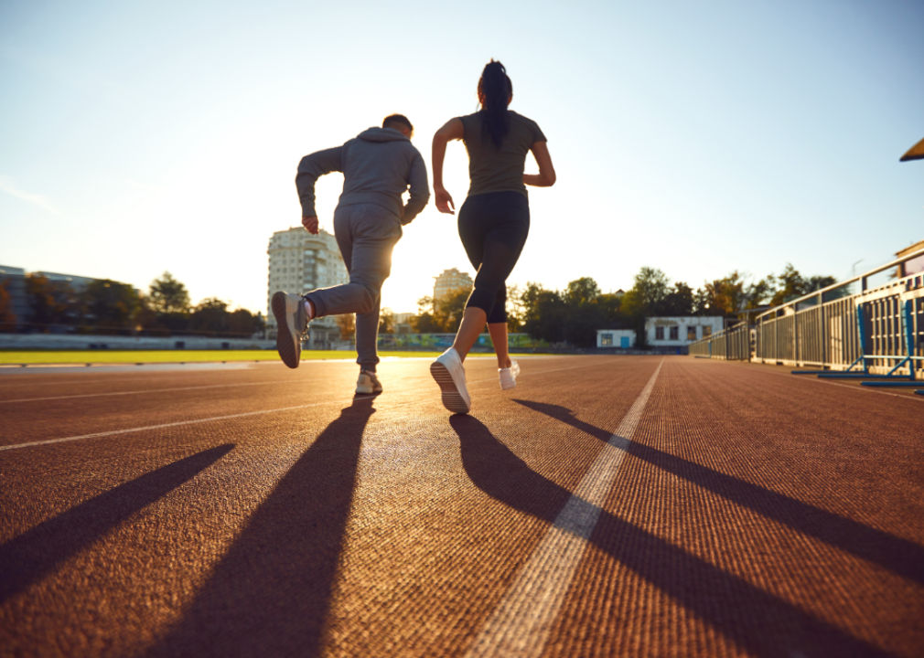 Two people running on an empty track at either sunrise or sunset.
