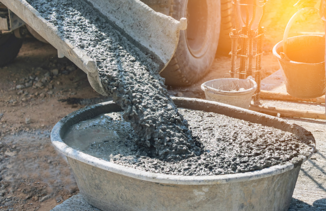 Close-up of concrete mixer truck pouring concrete into large basin.