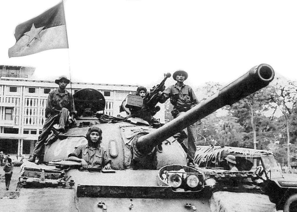 A North Vietnamese Army tank flying the NLF flag at the Presidential Palace during a victory parade through the streets of Saigon.