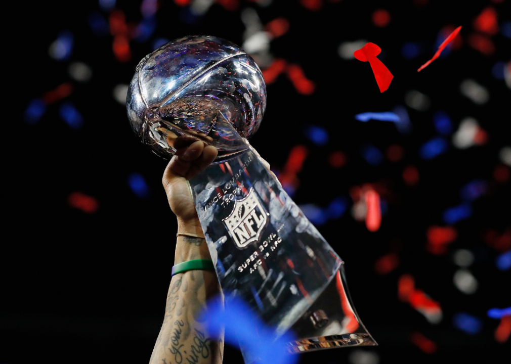 A New England Patriots player raising the Vince Lombardi Trophy.