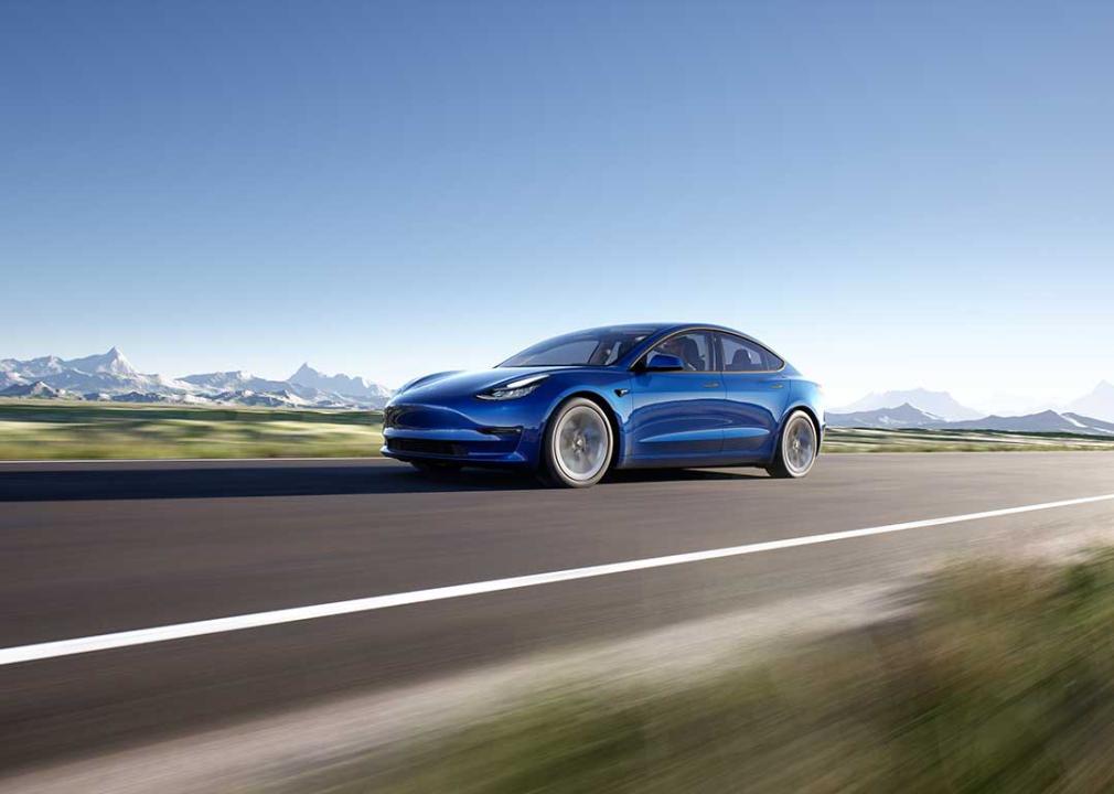 blue Tesla model 3 driving on road