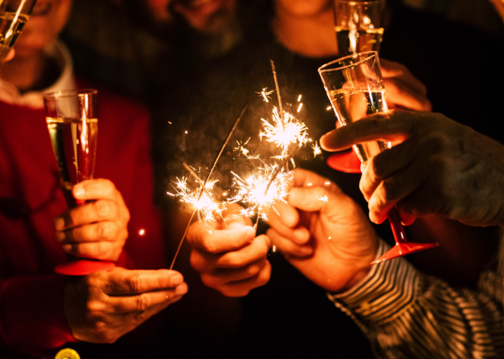 A cluster of hands holding champagne glasses and sparklers.