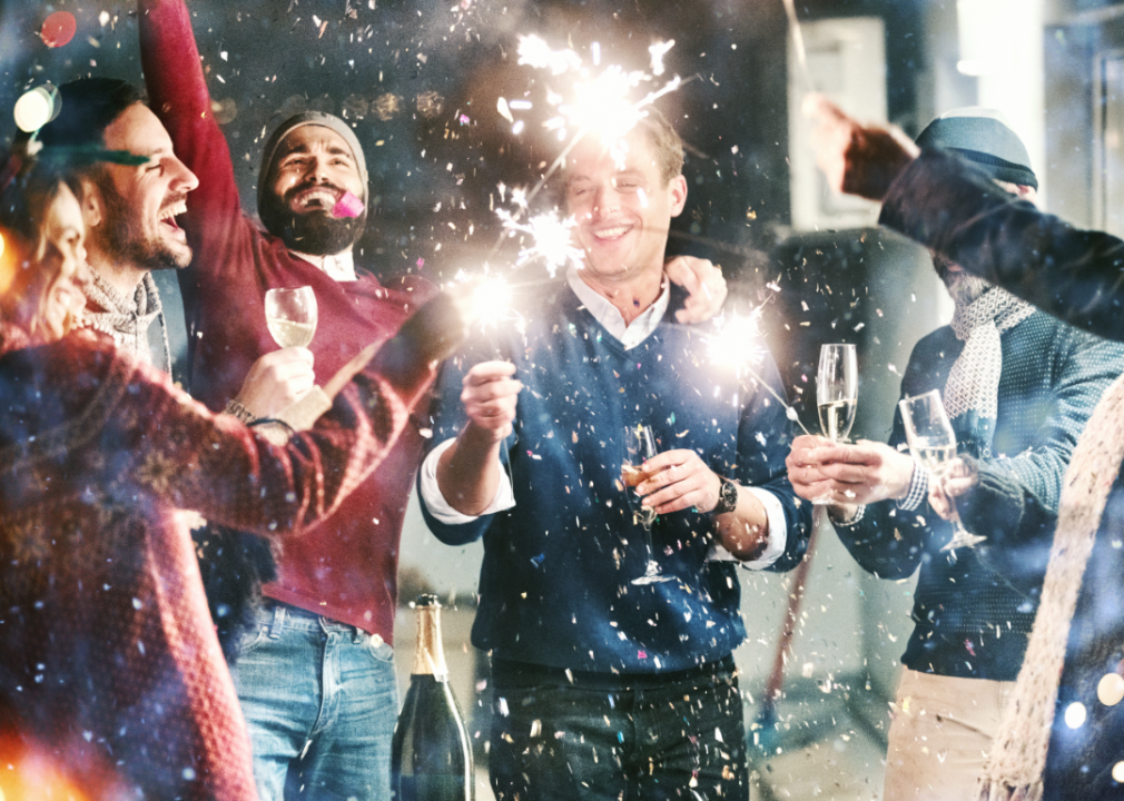 A group of people laughing and waving sparklers in the air.