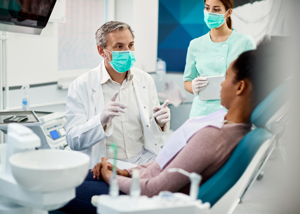Mature male dentist speaking with woman patient.