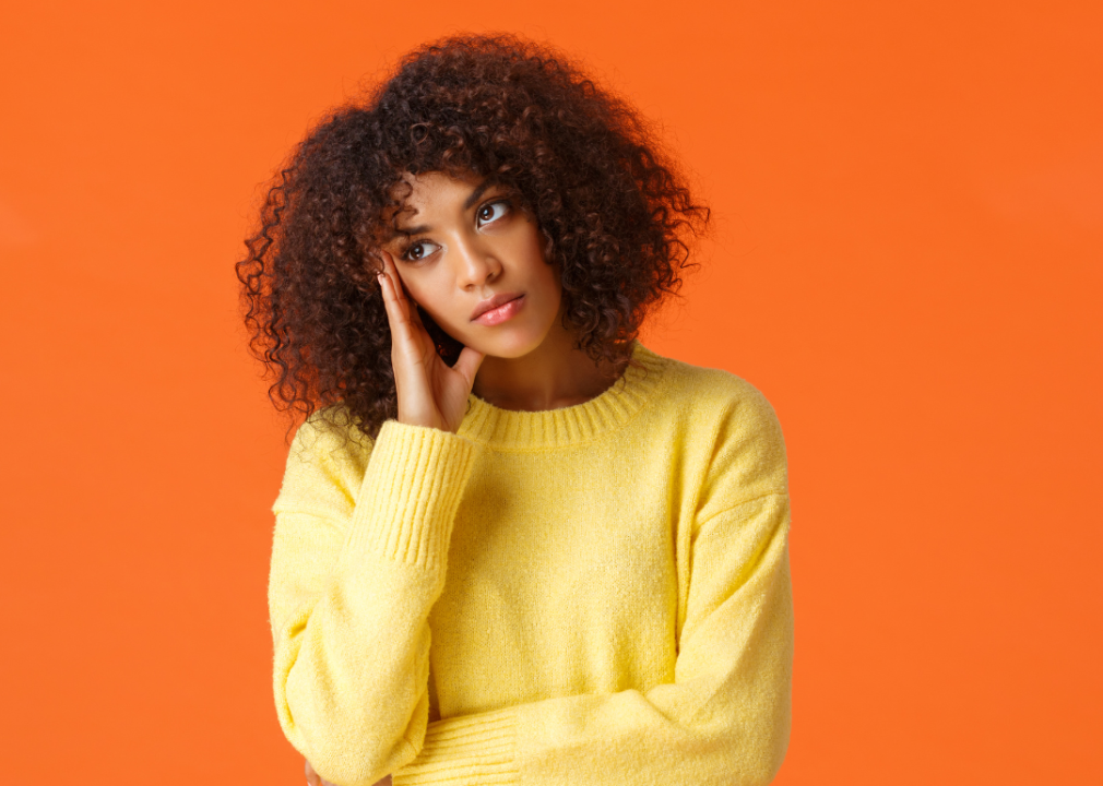 Black woman in yellow sweater with her hand pressed to her face in disinterest.