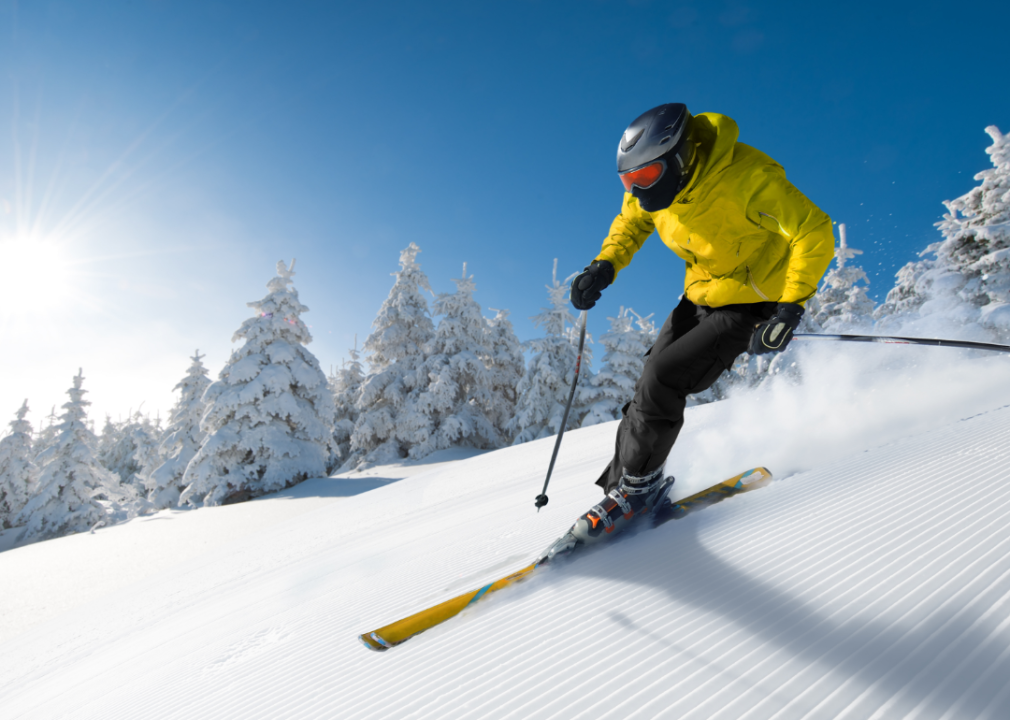 A skier in bright yellow jacket skiing down a slope.