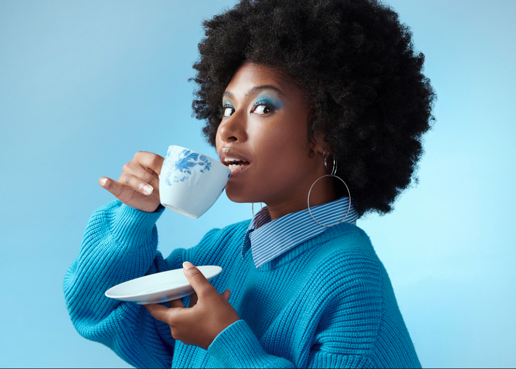 20 iconic slang words from Black Twitter that shaped pop culture A Black woman with a teacup against a bright blue background.
