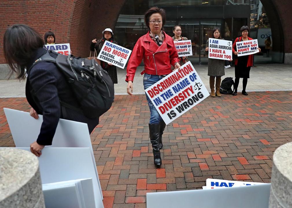 Ping Zhang holds a sign while demonstrating outside the John Joseph Moakley United States Courthouse on the opening day of Harvard University
