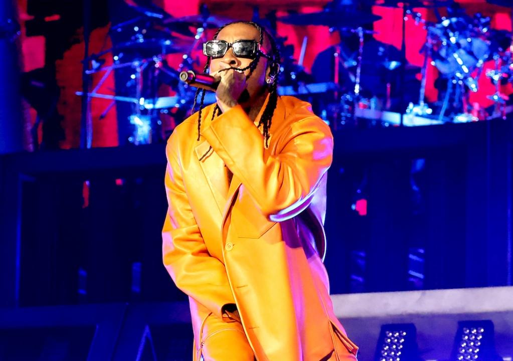 Rapper Tyra performing onstage in all-yellow outfit.