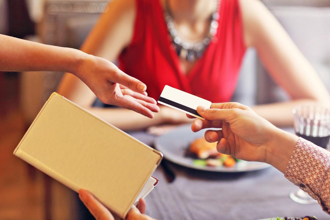 person paying for dinner with credit card with blurred image of date in the background