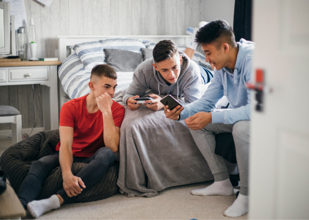 Three teens looking at phones in bedroom