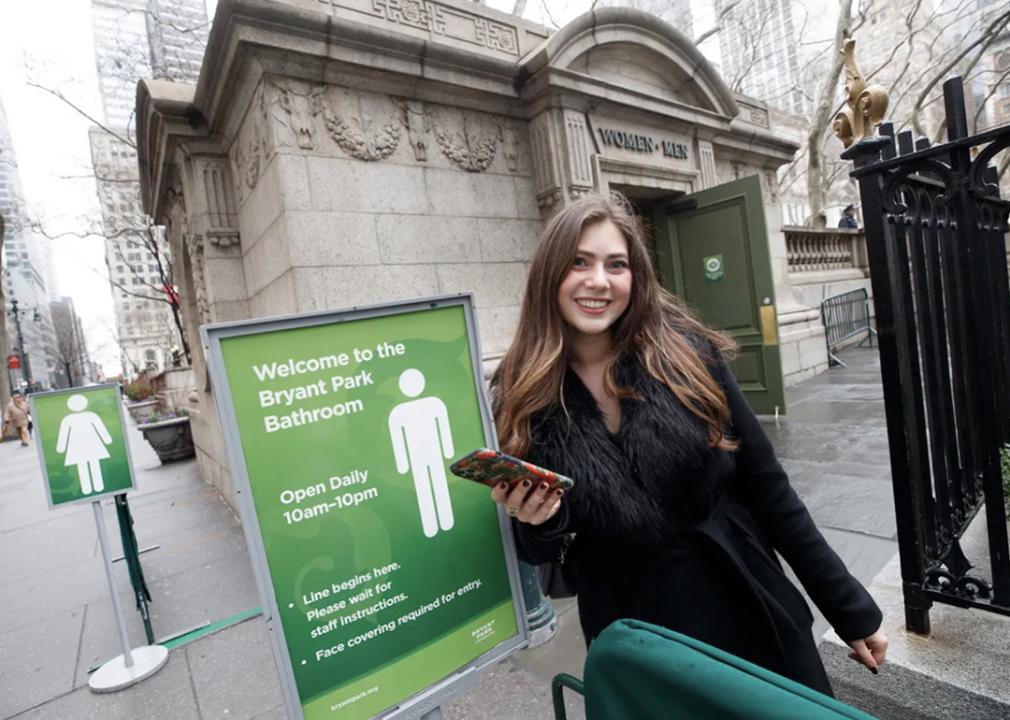 Teddy Siegel holding her phone while posing outside a Bryant Park Bathroom in New York City.
