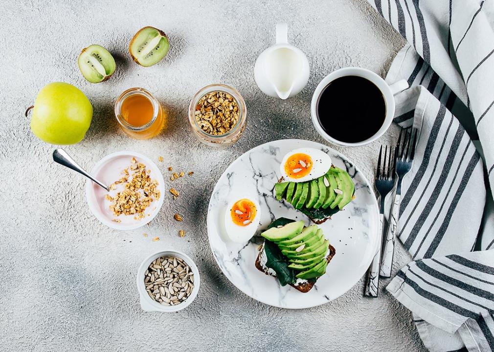 A flat lay photograph of a healthy breakfast concept including eggs, avocado and cup of coffee.
