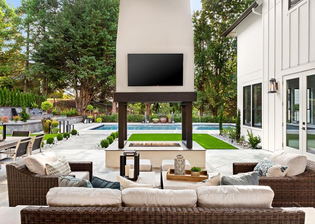 Outdoor TV is seen as part of a covered patio and with backyard furniture.