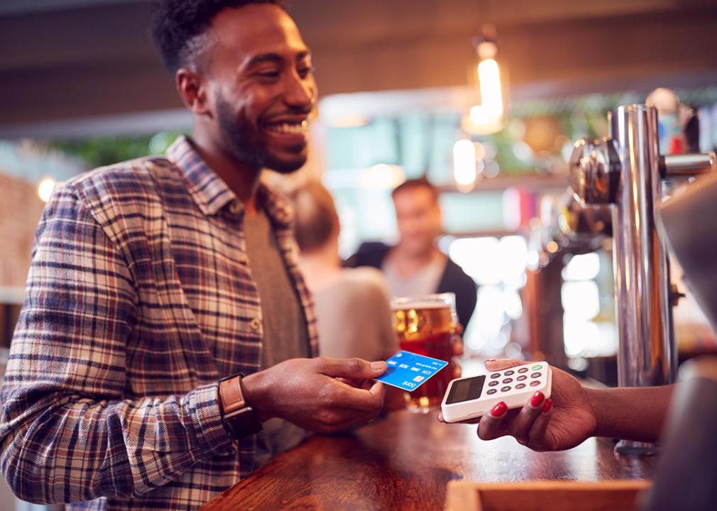 Person buying a drink from a bar with his credit card.