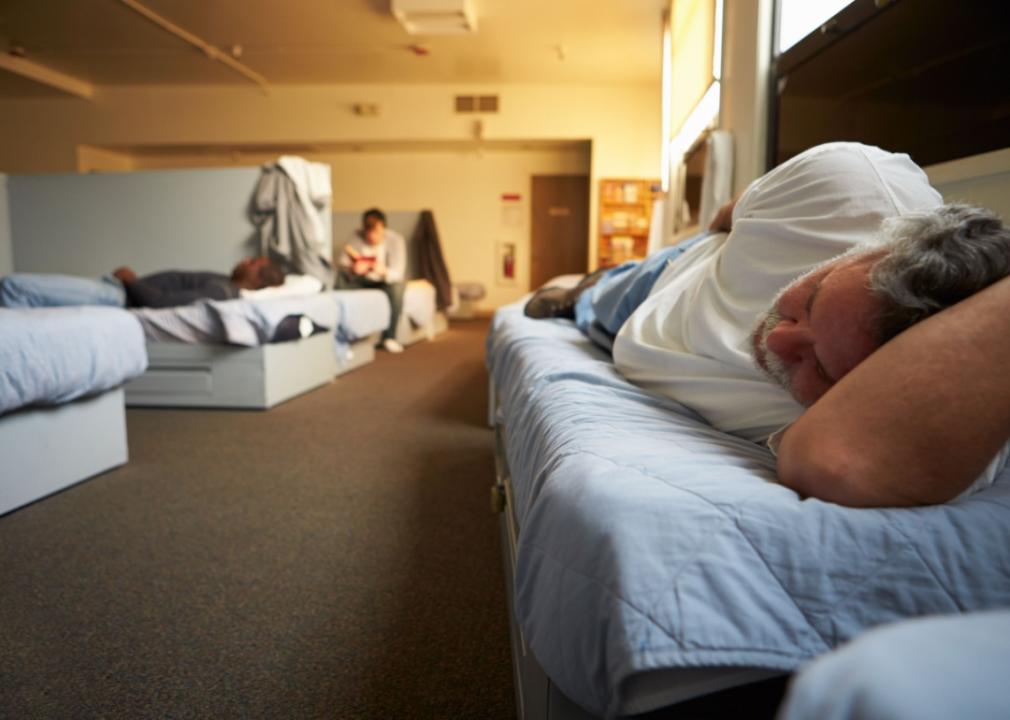 Men lying on beds in a homeless shelter.
