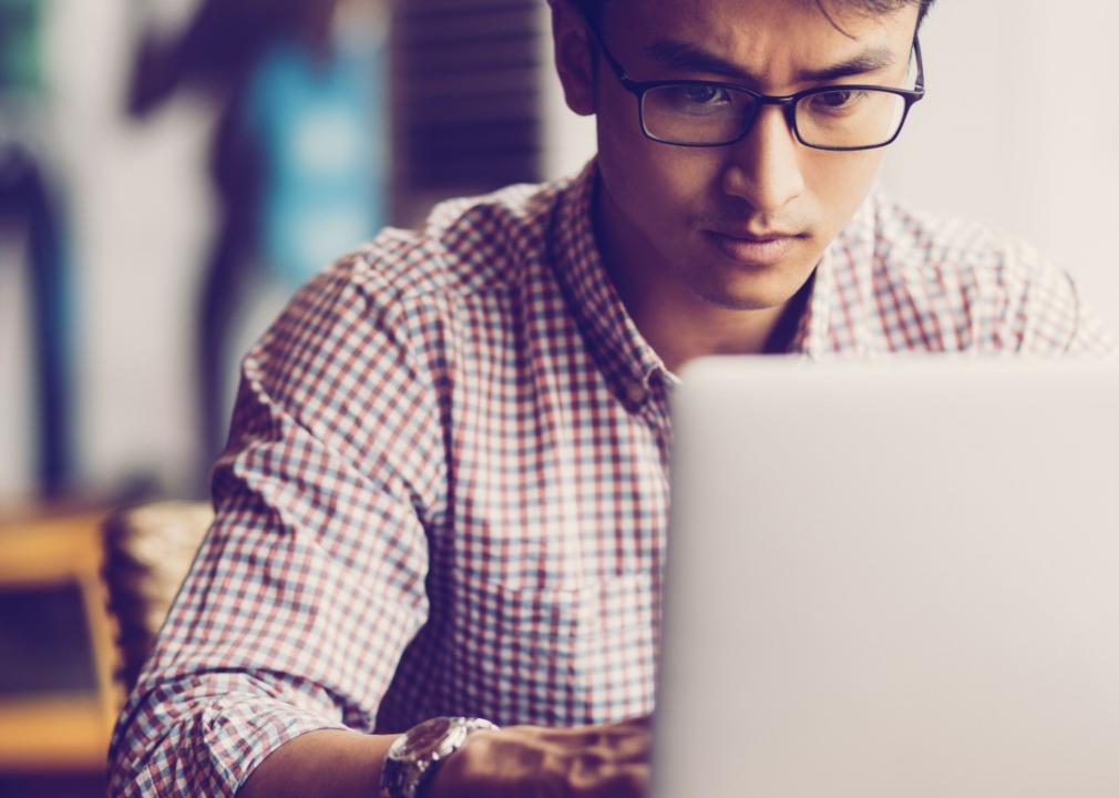 A young man concentrates as he types on his laptop at a cafe.