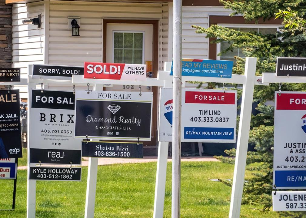 A row of signages are posted for homes for sale in Calgary, Alberta.