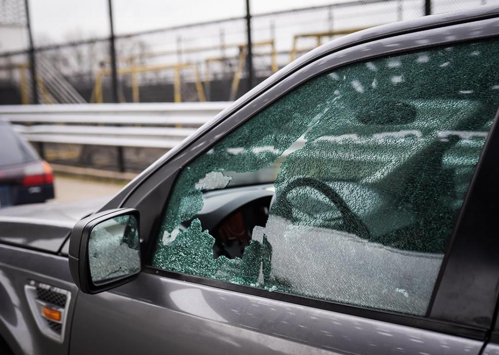 A close-up image of a driver's seat window showing damaged glass from car theft.