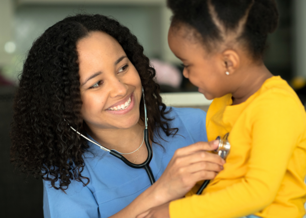 Woman nurse treating little girl.