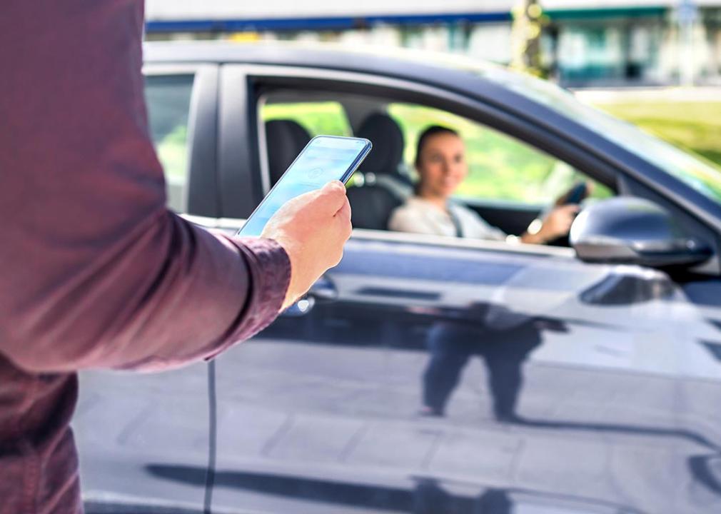 A person is on the phone while a Rideshare driver approaches for pickup.