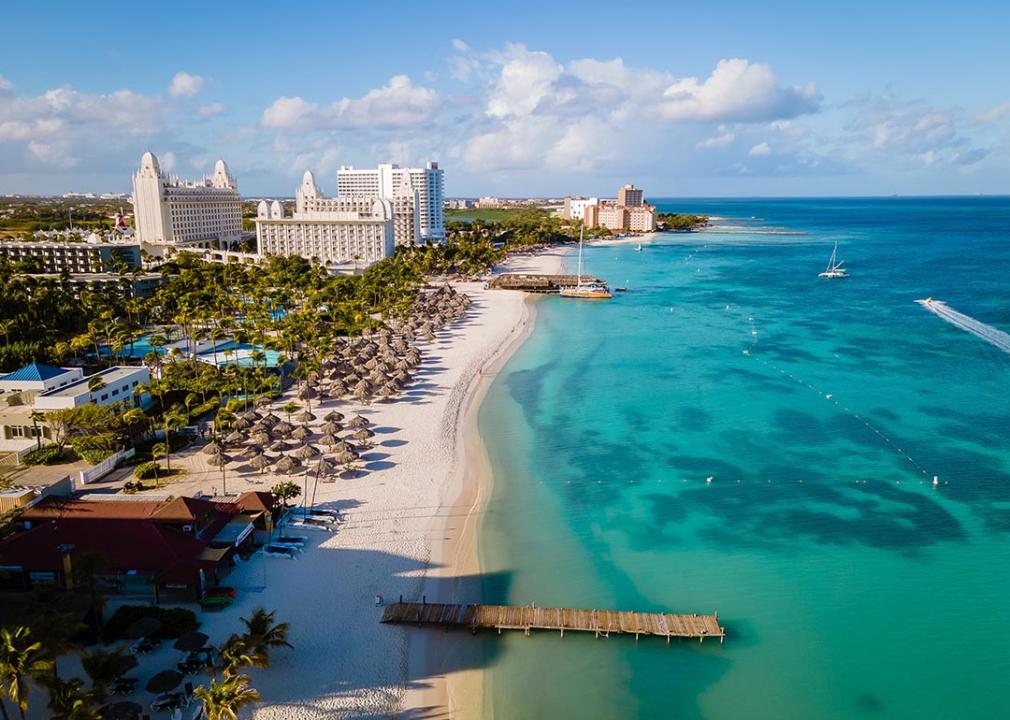 Aerial view of beach and resort in Aruba with blue green ocean on the right.