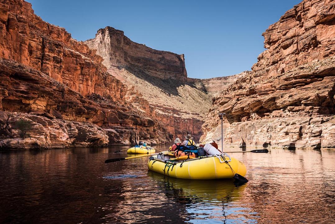 Whitewater Rafting on the Colorado River in Grand Canyon National Park, surrounded by red cliffs.