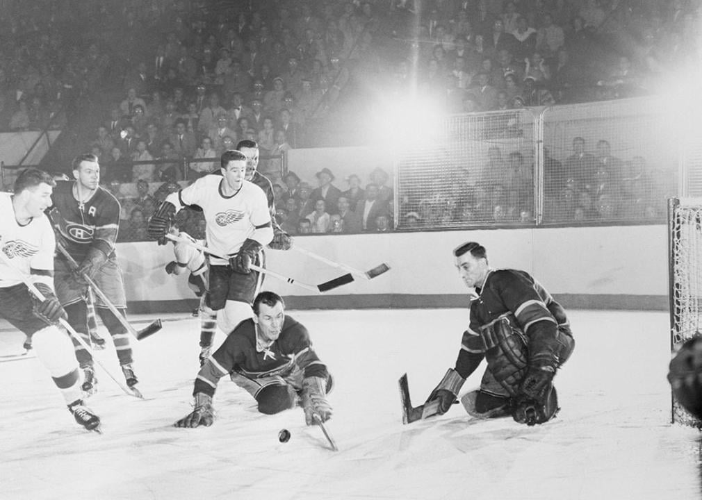 Canadiens' Butch Bouchard and goalie Jacques Plante (right) in the first game of the Stanley Cup series at Detroit. Other players are (from left): Vic Stasium, Detroit Red Wings; Ken Mosdell, Canadiens; Marcel Pronovost, Red Wings; and Tom Johnson, Canadiens (rear). The Wings won, 4-2.
