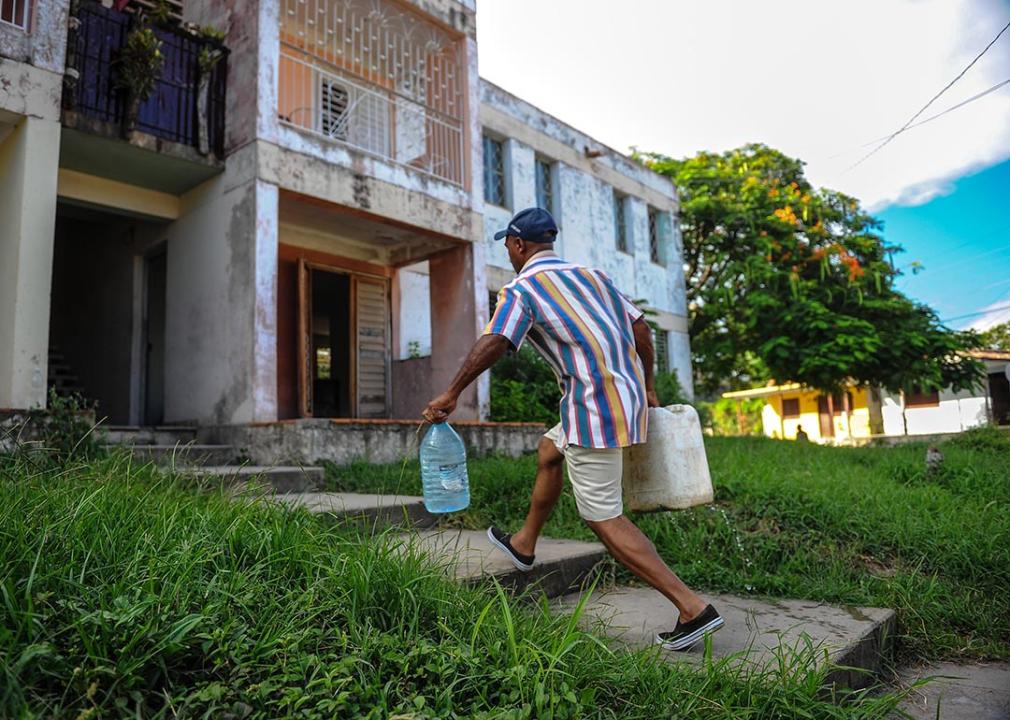 A man walks up concrete steps carrying plastic jugs of water in the Consolacion del Sur neighborhood in the Pinar del Rio province, Cuba.