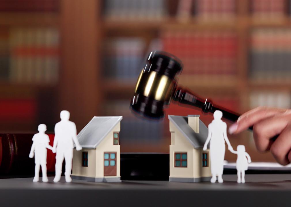 A cut-out illustration of a family of four and a house are divided by an attorney