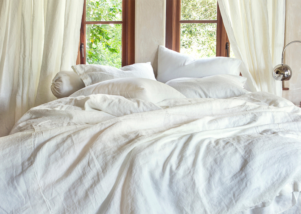 A queen size bed laid cozily with white linen sheets.