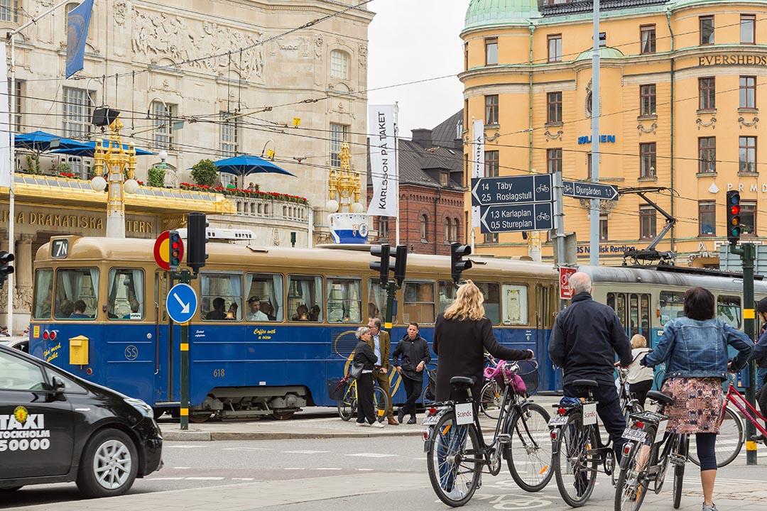 Traffic, bikes, and taxis cross traffic in a Swedish city center. 