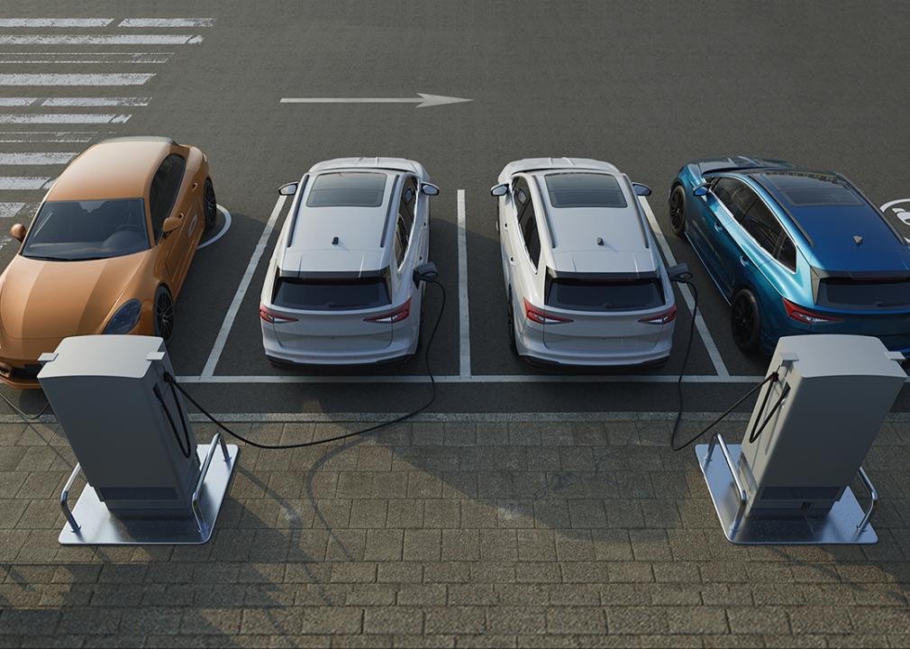 A row of four electric cars getting recharged at an EV charging station.