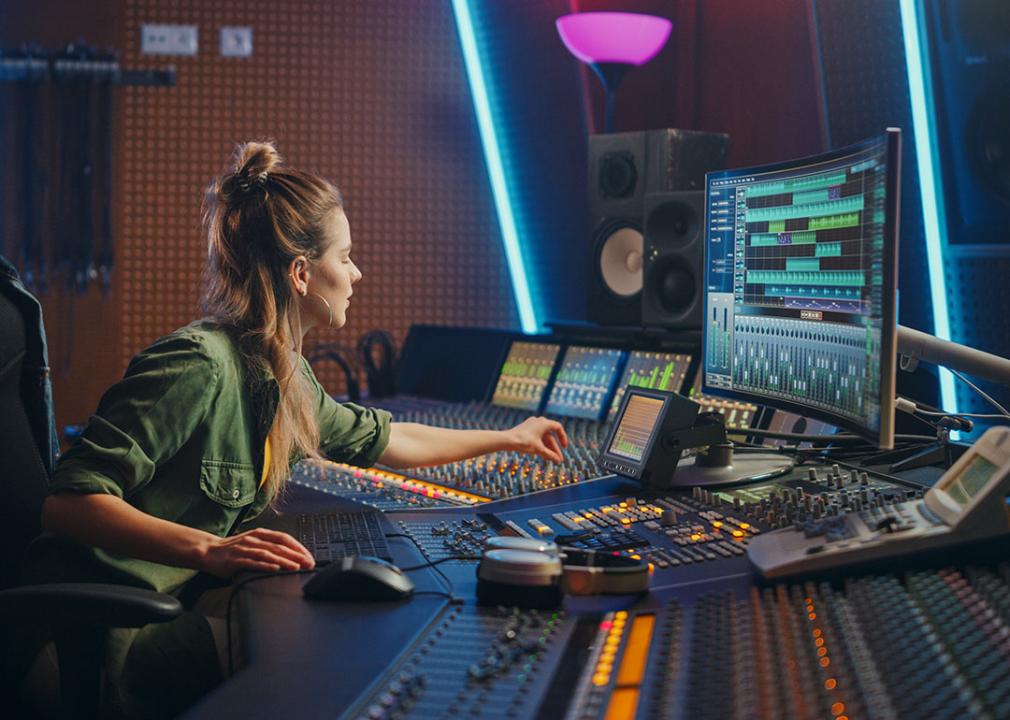 A female DJ inside a sound booth working on production.