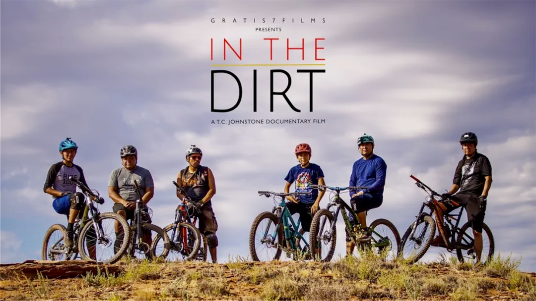 Key art for In the Dirt film documentary depicting six mountain bikers and their bikes against a cloudy sky.