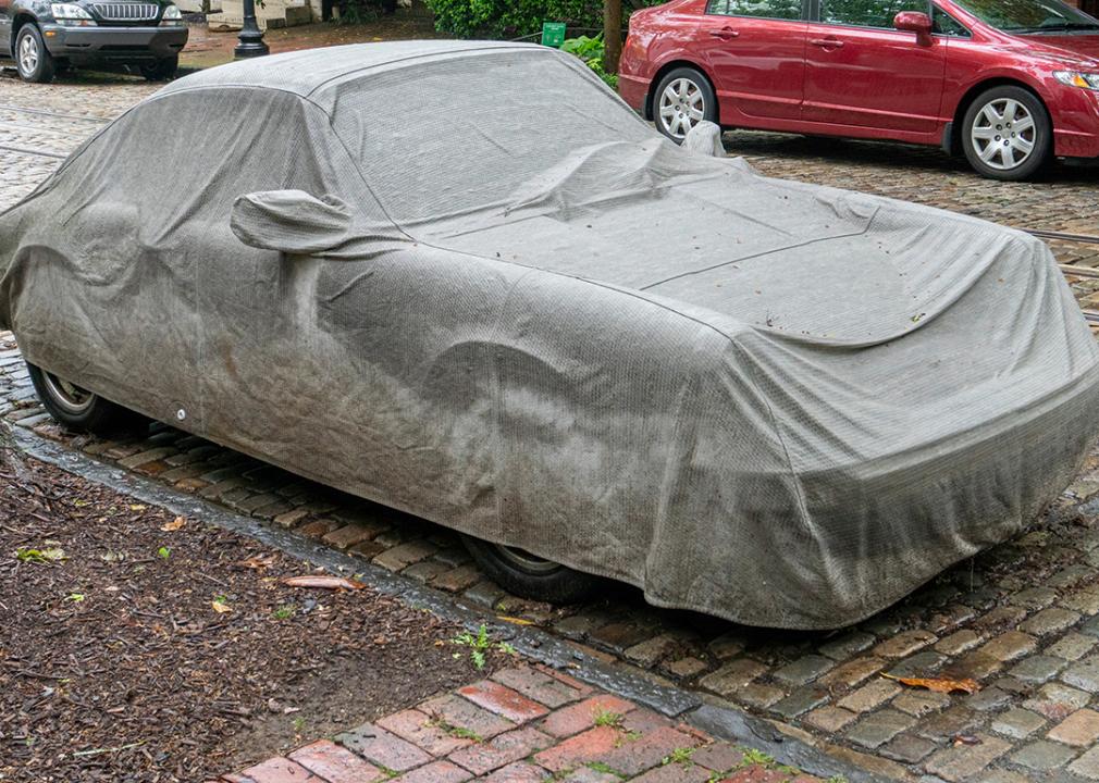 A car covered by a grey tarpaulin.