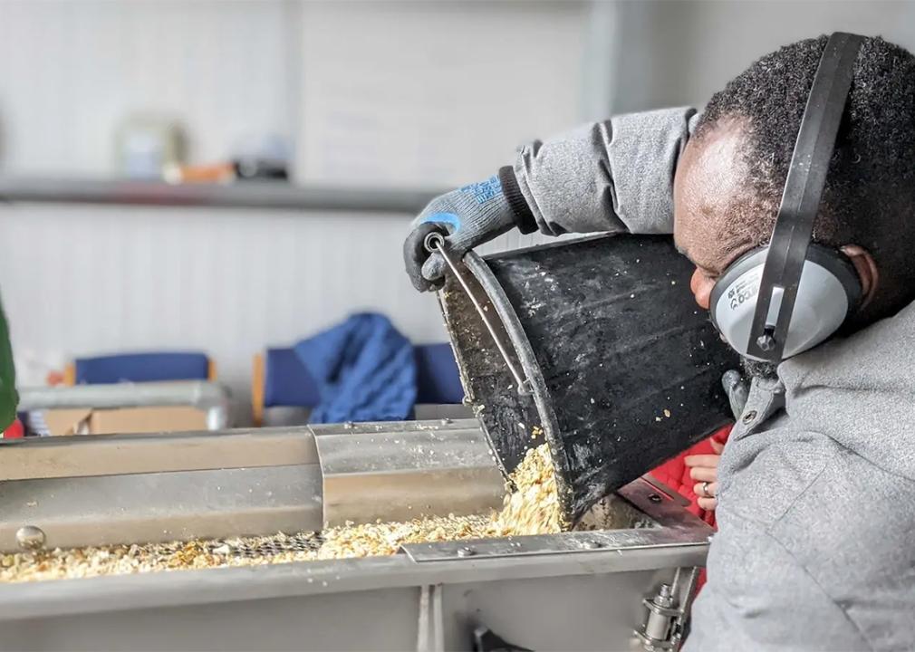 A LeftCoast worker pouring a bucket of discarded shells into a machine.