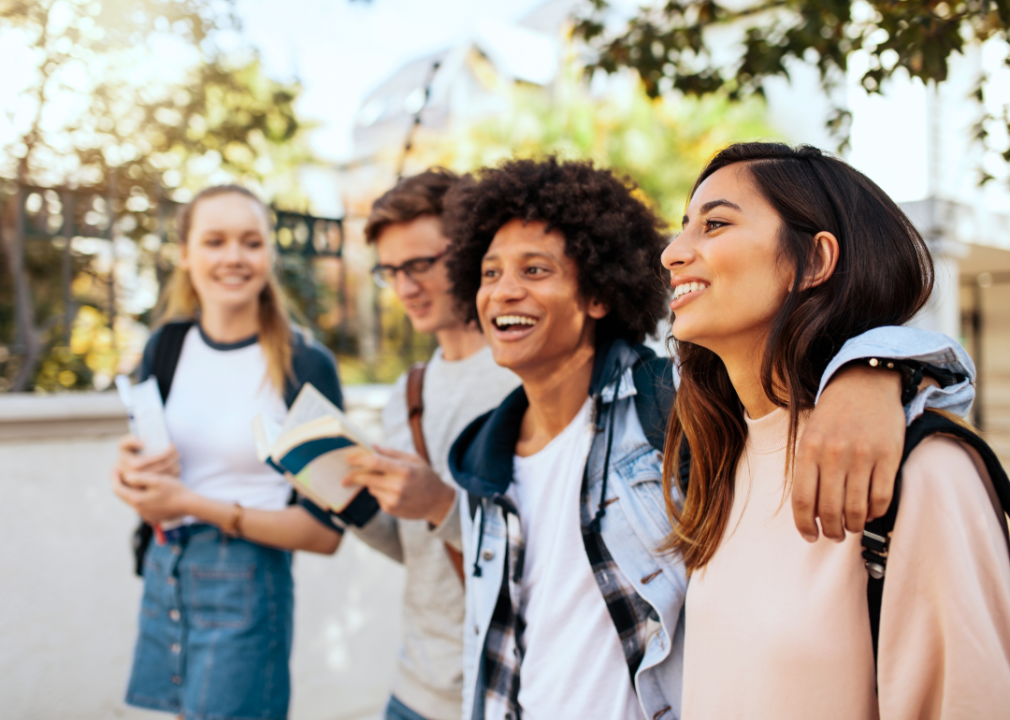 Four college students walk together on campus smiling.