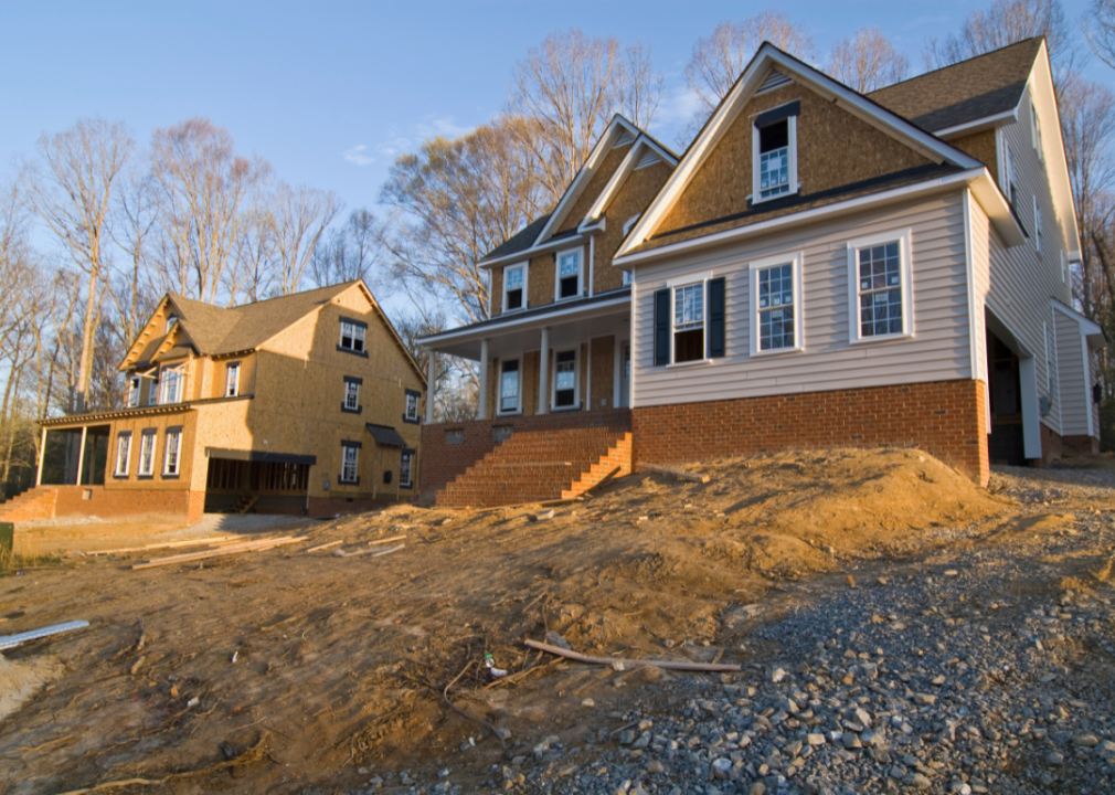 Two new homes that are almost finished being built sit next to each on a lot.