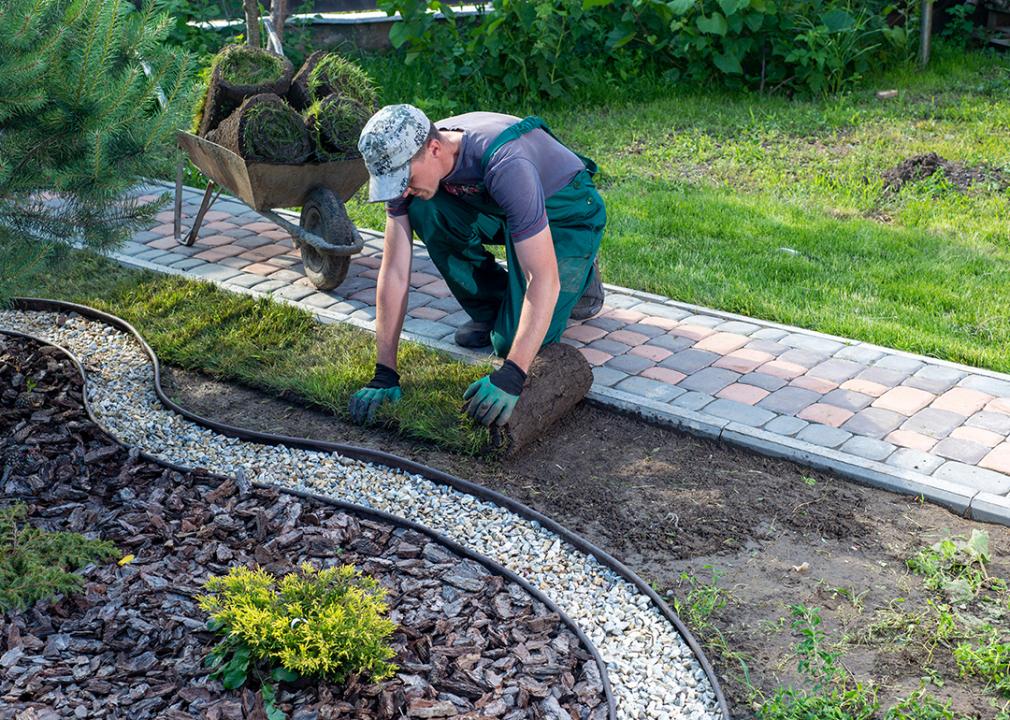 A landscaper doing maintenance on a lawn curb.