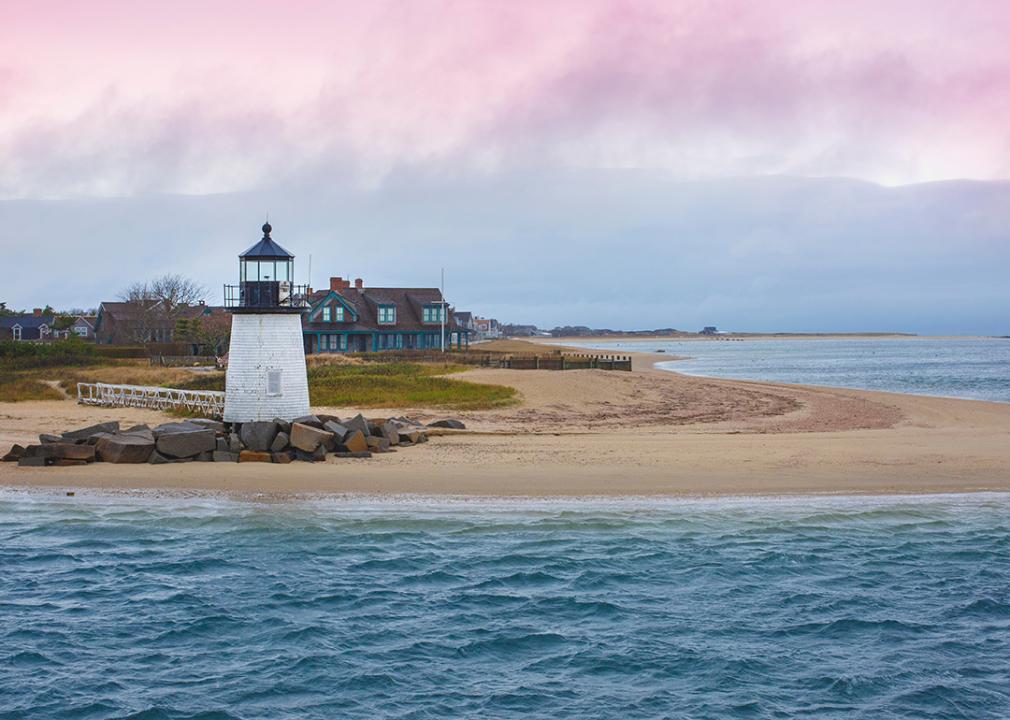 The Brant Point Lighthouse and pink clouds are over a Nantucket beach in Massachusetts.