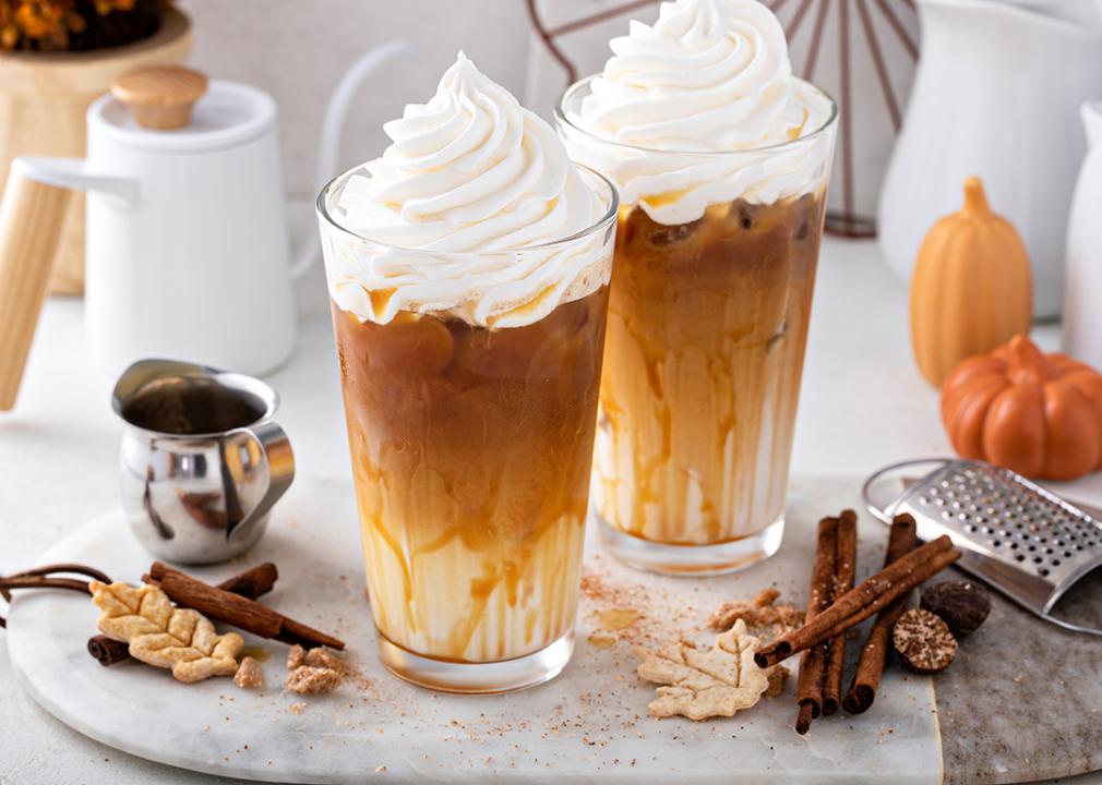 Two glasses of pumpkin spice lattes surrounded by its common ingredients.