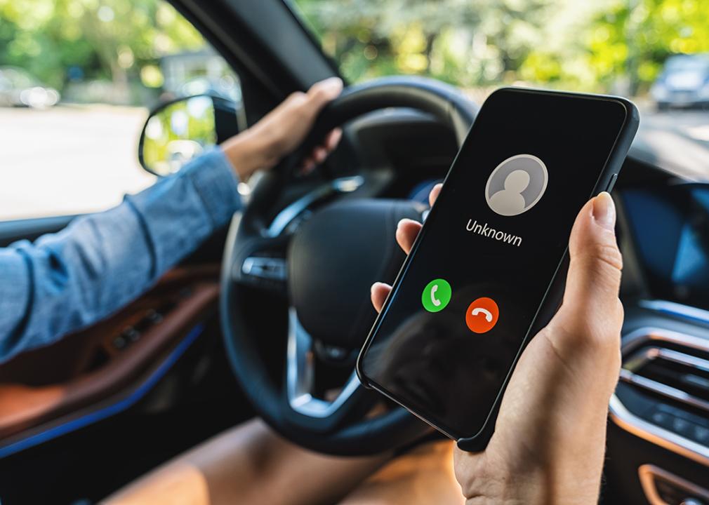 Person inside a car looking at an incoming unknown call.