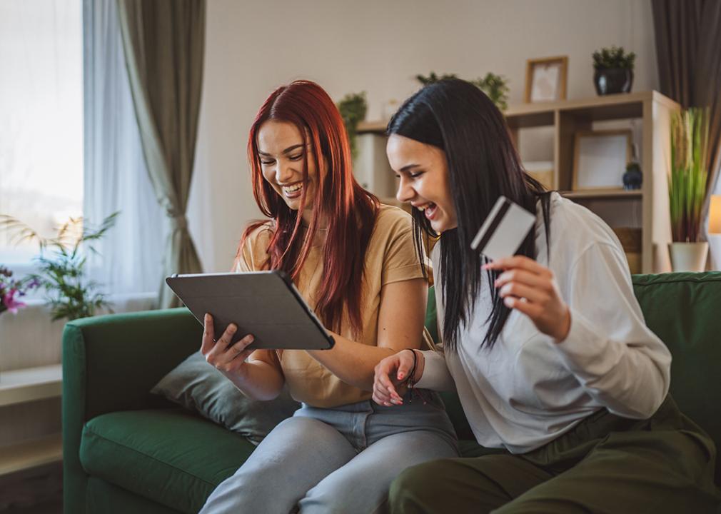 Two Gen Z women browsing online using a tablet and using a credit card.