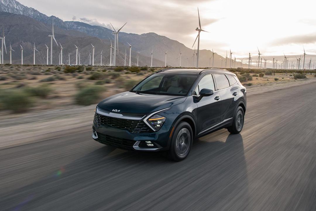 Photo of Black Kia Sportage Hybrid driving with windmills in the background in the desert.