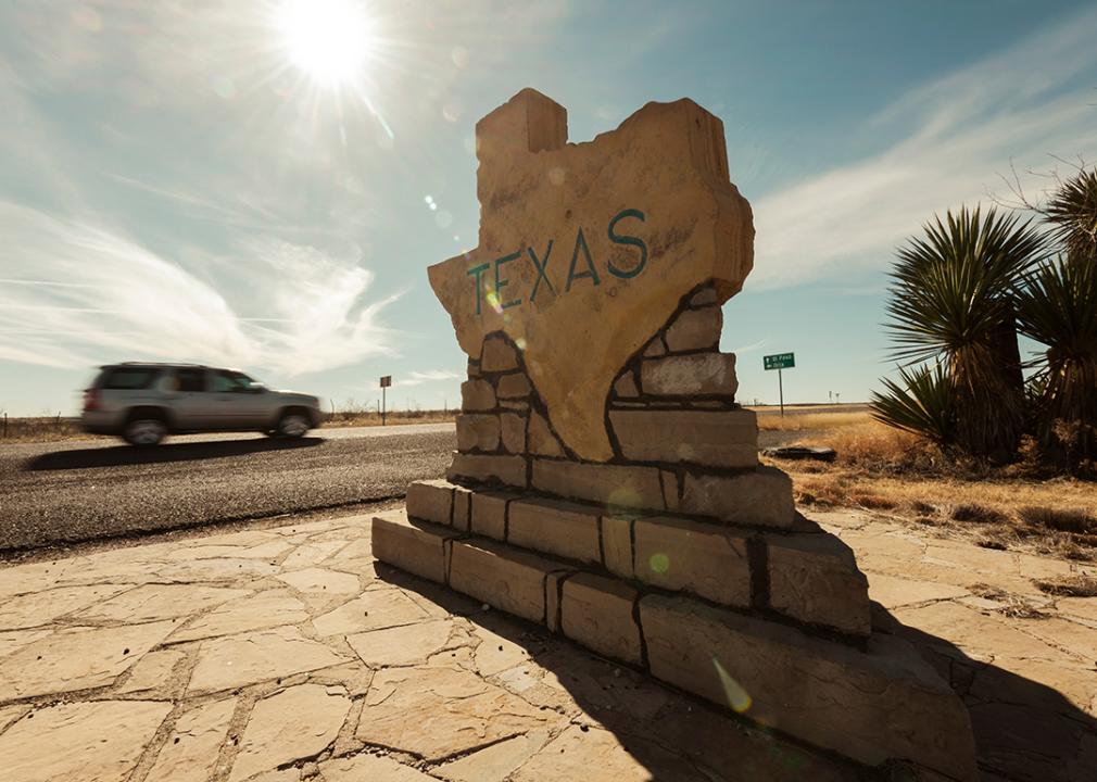 A car speeds along past a border sign for the state of Texas.