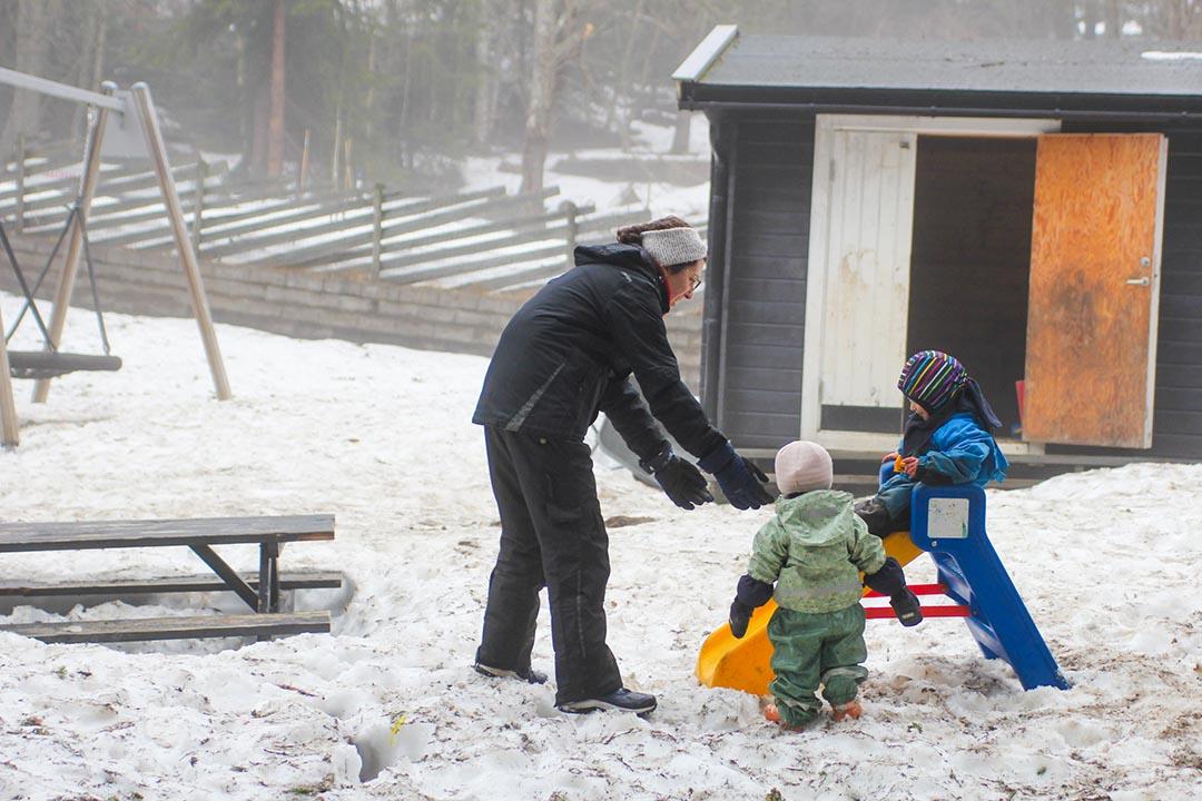 A teacher at the Turi Sletners child care program in northwest Oslo, helps children as they play in the snow. 