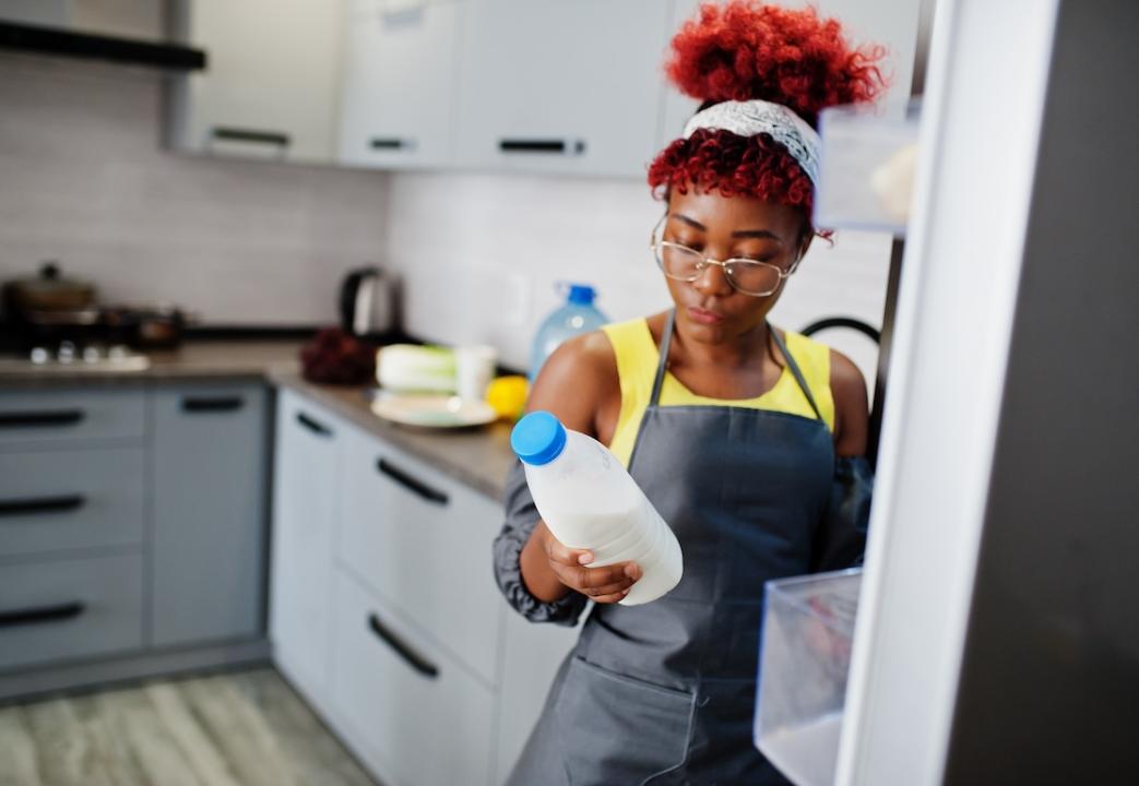Woman holding a carton of milk from the refrigerator.